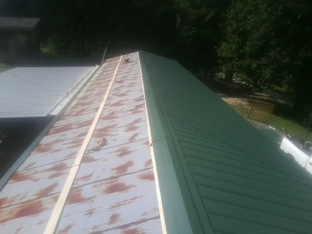 Old rusted panels beside newly installed green metal roofing — Wind Damage Roof Repair by Roofing Brothers in Leeds