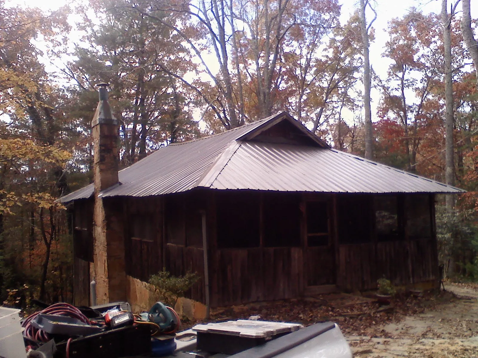 Brown metal hip roof on an old cabin with a stone chimney in Leeds