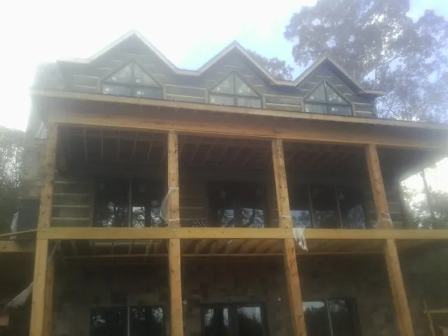 Dormers and porch framing on a large log home under construction — Roof Coating work by our crew in Leeds